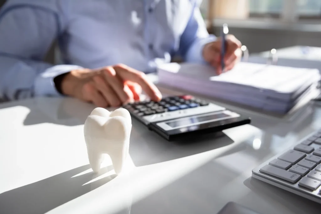 Bookkeeping for dentists — a dental practice's books being reconciled on a calculator beside a model tooth